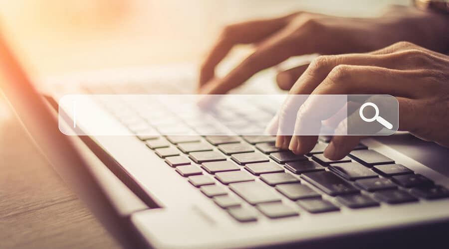 Close up of hands typing on laptop with translucent SEO bar superimposed